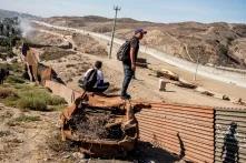 Migrantes hondureños observan hacia el territorio estadounidense. El muro blanco del fondo es utilizado por la Patrulla Fronteriza para recorrer en vehículo la frontera, pero ya se considera territorio estadounidense.  