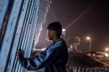 Esteban Orellana, de 15 años, observa a través del muro hacia el lado estadounidense. Orellana intentaba cruzar esa misma noche, pero la presencia de la Patrulla Fronteriza lo hizo cambiar de opinión. El cruce por la zona de playas, un sector vigilado habitualmente y sobrevigilado desde la llegada de las caravanas, es un despropósito, un síntoma de la desesperación de quienes llevan semanas varados en esta ciudad. 