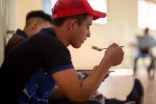 Santos, de 22 años, toma sus alimentos durante el almuerzo, este día descansa junto a su primo Lenin de 19 años en la Casa del Migrante José. Los dos primos han decidido migrar porque en Siguatepeque el desempleo no les permite tener mejores condiciones de vida. Esquipulas, 1 de febrero 2020. Foto: Martín Cálix.