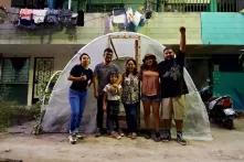 Jovenes en zona suburbana frente a un pequeño invernadero. 