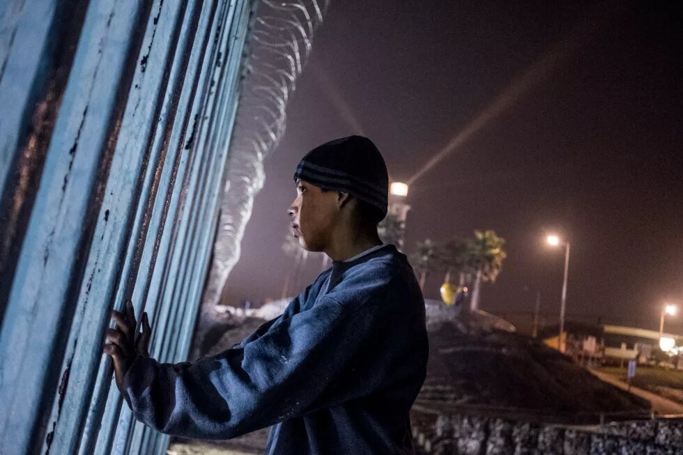 Los éxodos de refugiados en América. Esteban Orellana, de 15 años, observa a través del muro hacia el lado estadounidense. Orellana intentaba cruzar esa misma noche, pero la presencia de la Patrulla Fronteriza lo hizo cambiar de opinión. El cruce por la zona de playas, un sector vigilado habitualmente y sobrevigilado desde la llegada de las caravanas, es un despropósito, un síntoma de la desesperación de quienes llevan semanas varados en esta ciudad.