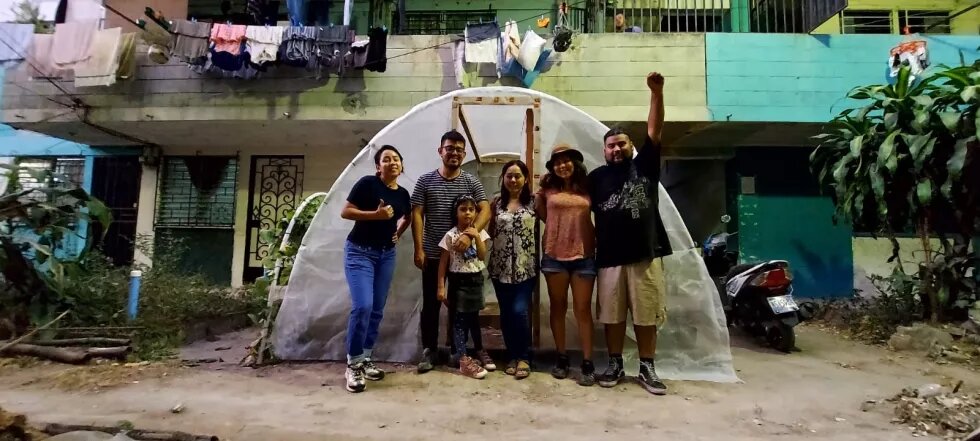 Micelio Suburbano El Salvador Jovenes en zona suburbana frente a un pequeño invernadero.