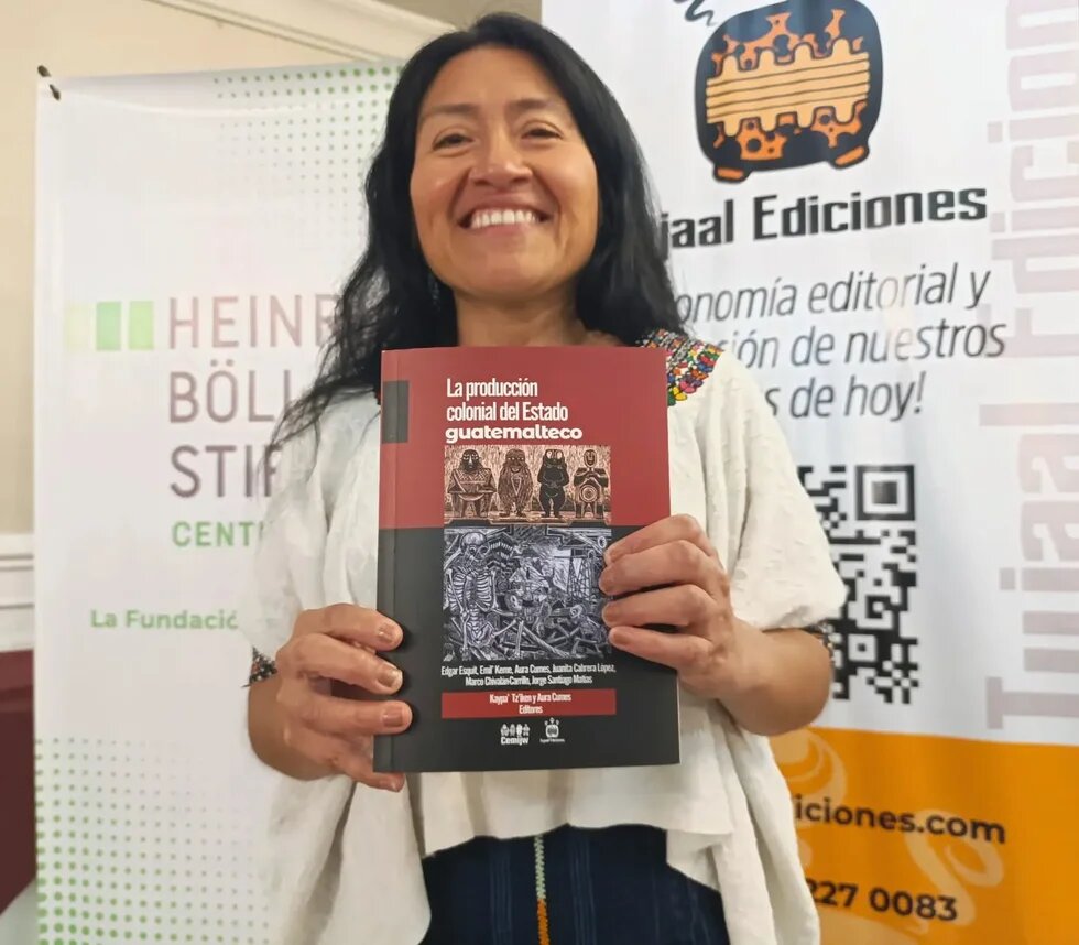 Se muestra una mujer indígena sosteniendo la publicación "La Producción Colonial del Estado Guatemalteco"